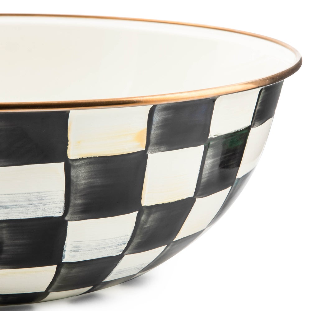 Close-up of an extra large bowl with hand-painted black and white checks and a bronzed steel rim.