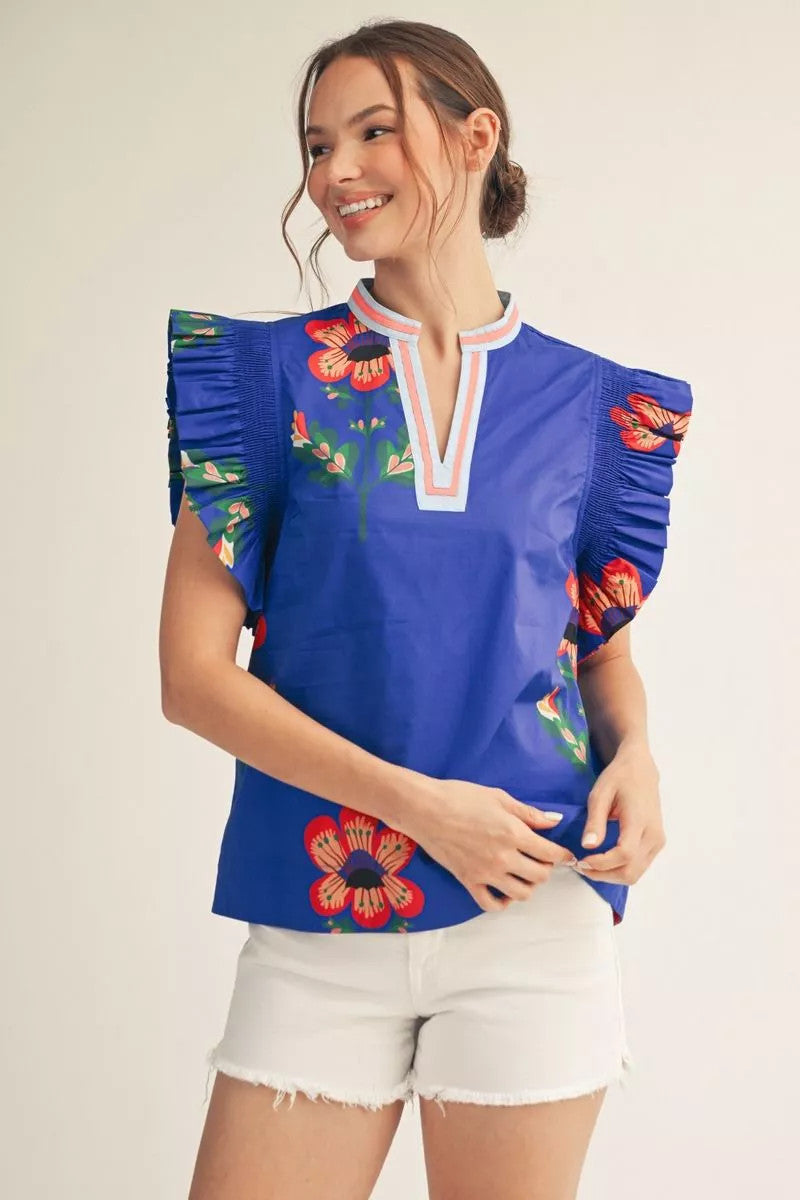 Women's woven top with floral print, ruffled sleeves, smocking shoulders, and notched V neckline in solid contrast.