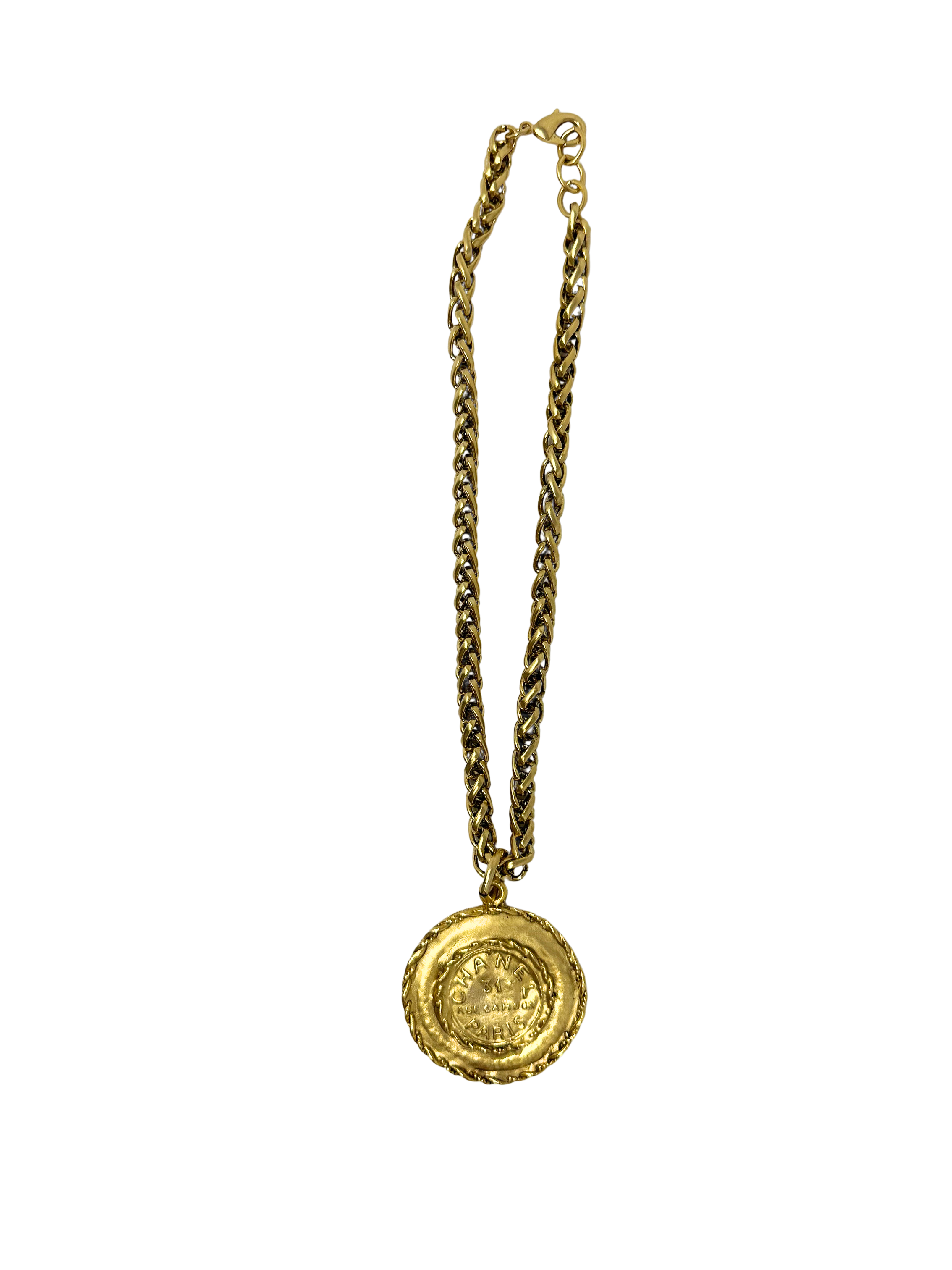 Gold chain necklace featuring a braided coin pendant with embossed designer text.