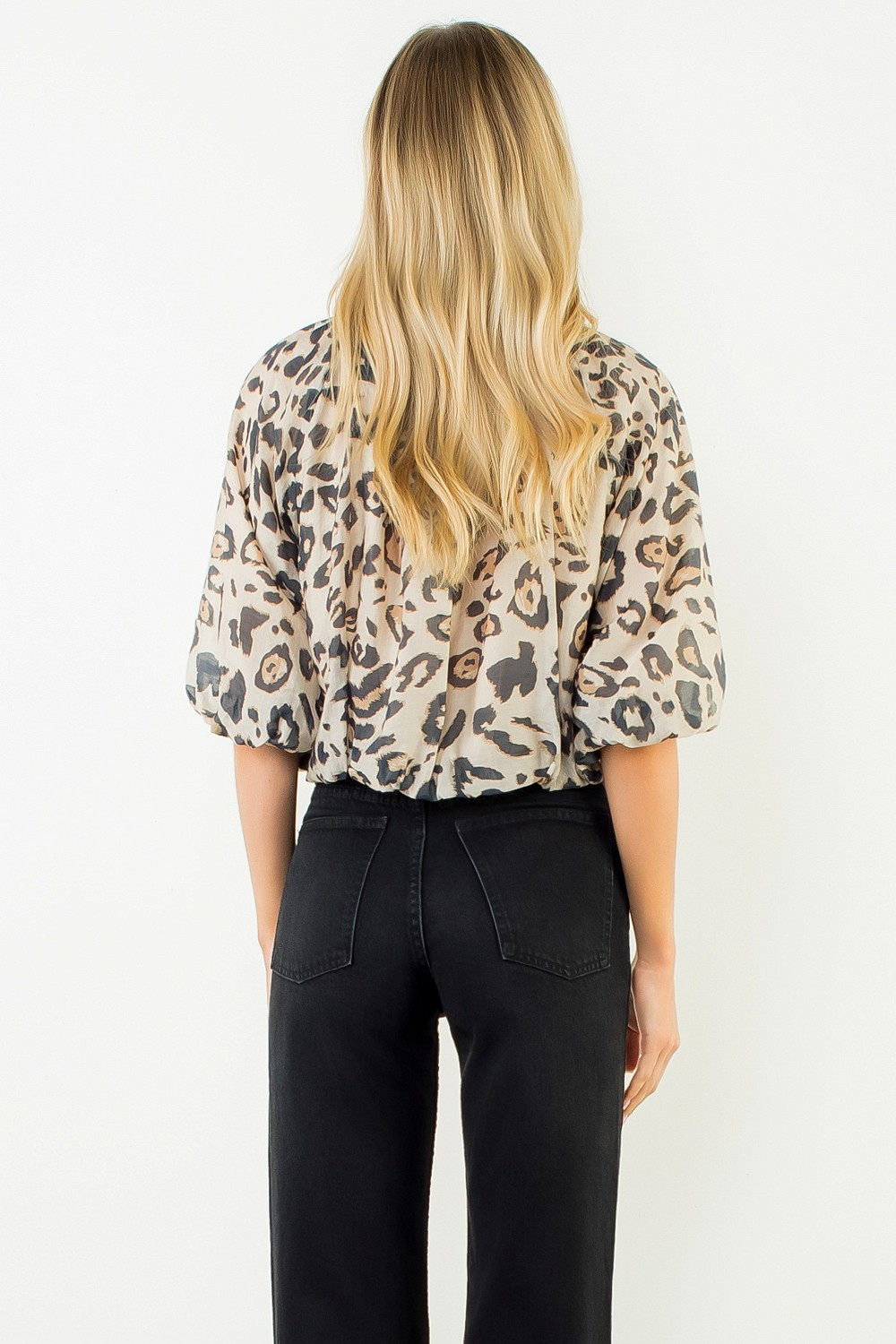 Back view of a woman wearing the Elise leopard print puff sleeve top and black jeans.