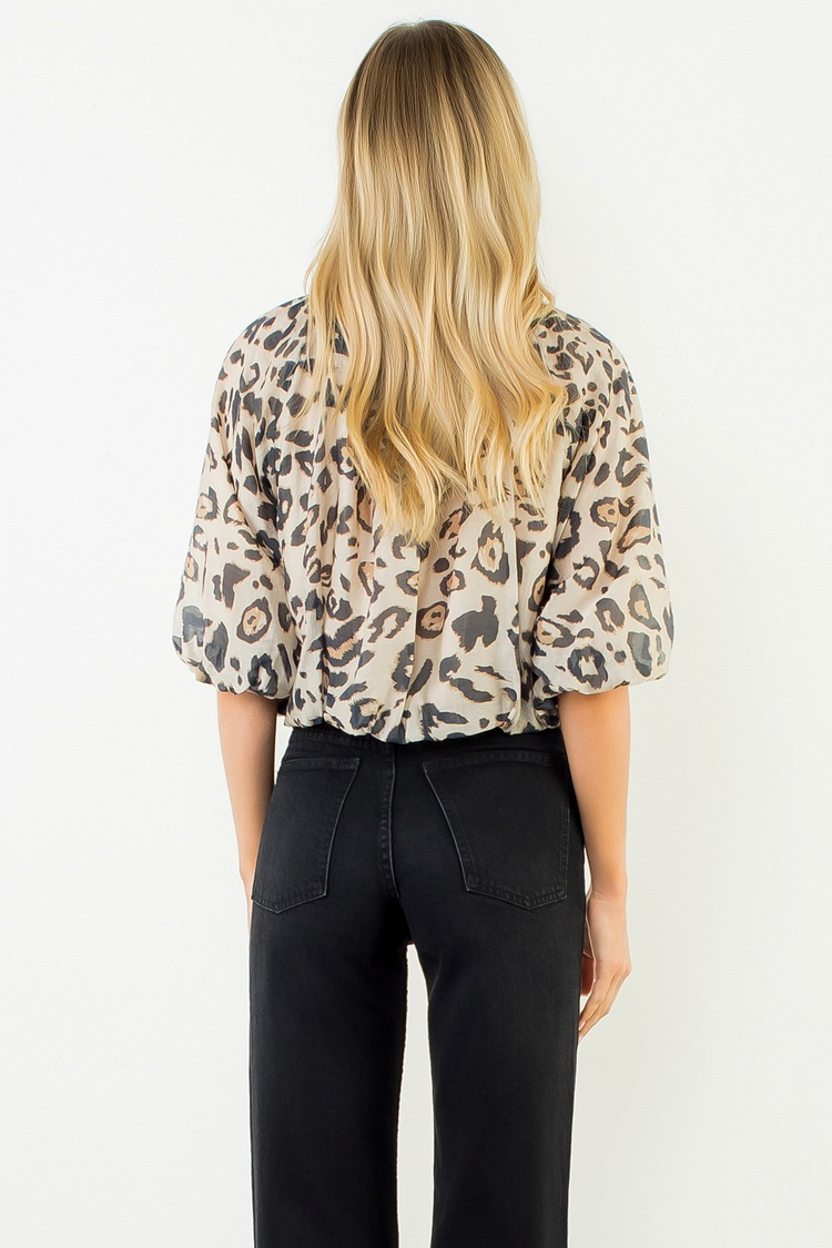 Back view of a woman wearing the Elise leopard print puff sleeve top and black jeans.
