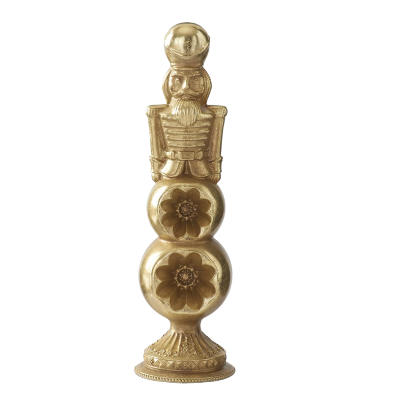 Gold nutcracker figure standing on a tiered ornament finial base with carved floral details.