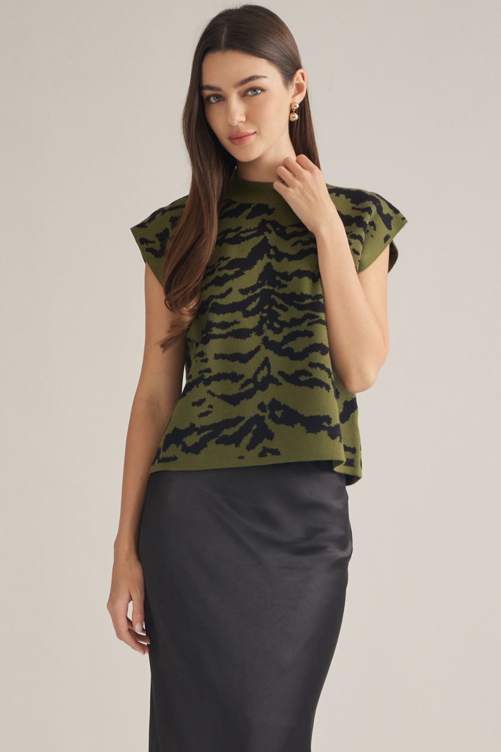Woman wearing the Amelia olive green and black animal print sleeveless knit top with a black skirt.