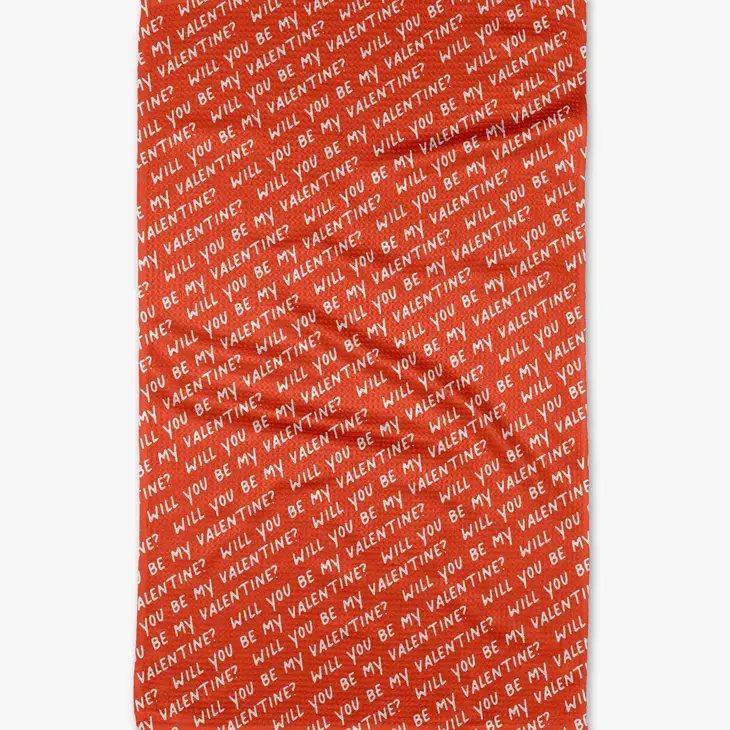 Red waffle weave tea towel with white diagonal text repeating "WILL YOU BE MY VALENTINE?".