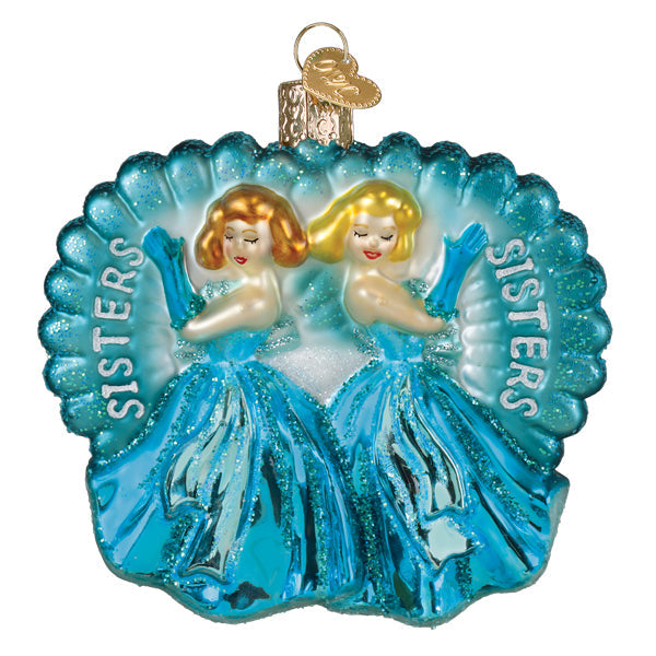 Glass ornament featuring two sisters in blue dresses and gloves inside a teal scalloped shell.
