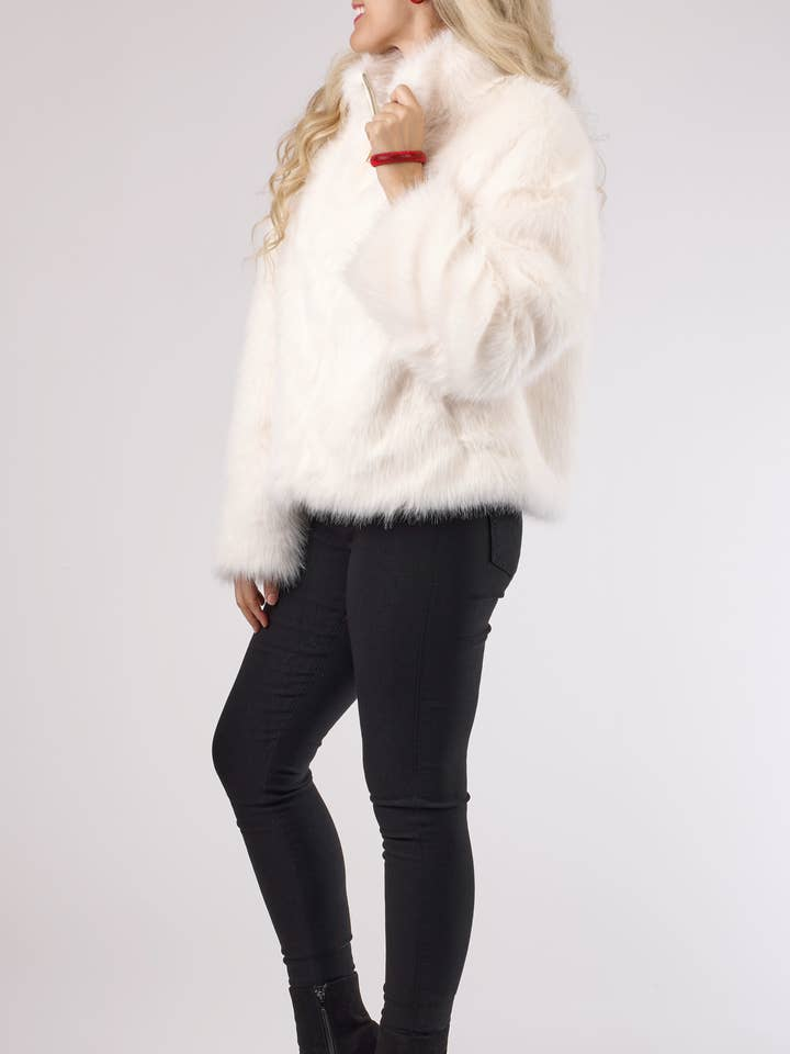 Woman wearing a white dressy faux fur jacket with a zipper closure and black pants.