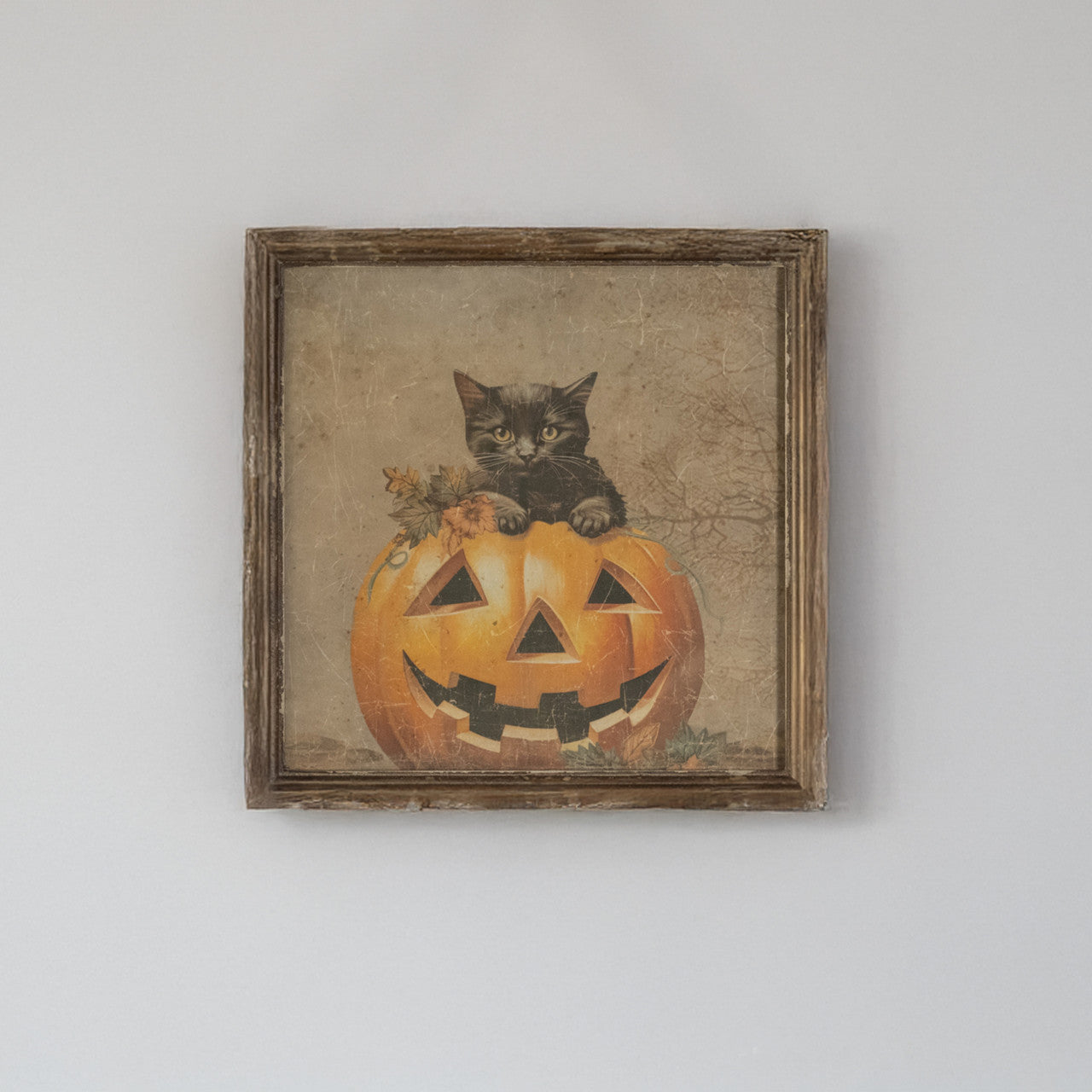 Vintage-style framed print featuring a black kitten sitting inside a carved jack-o'-lantern.