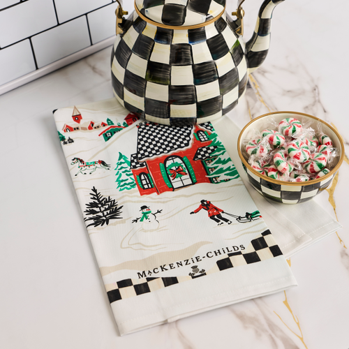 Alpine Village Printed Dish Towel featuring a winter scene with a snowman, house, and skaters.