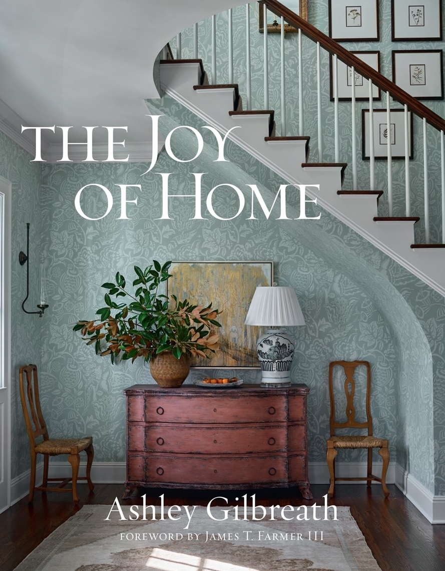 The Joy of Home book cover by Ashley Gilbreath featuring a decorated entryway with a red dresser.