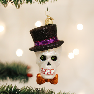 Glittery white skull ornament wearing a black top hat with purple band and an orange bow tie.
