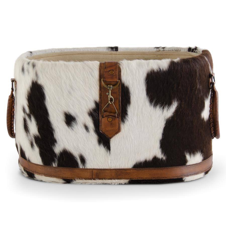 Oval black and white cowhide basket with brown leather trim, handles, and a metal clasp.