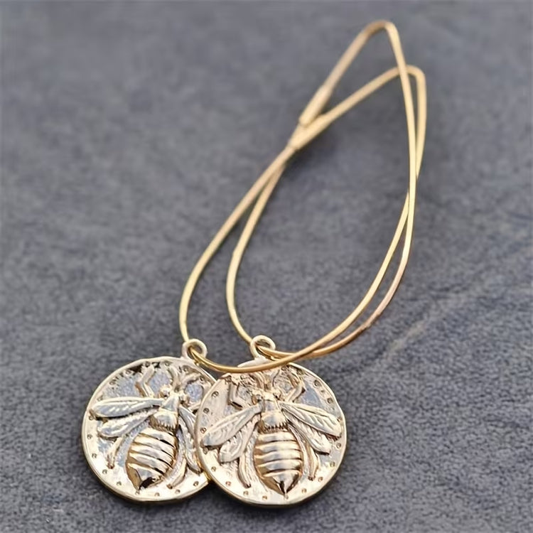 Round gold-tone boho earrings with detailed bee charms on oversized teardrop wires.