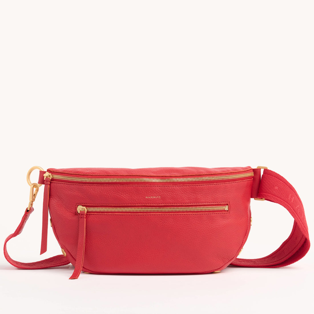 Oxblood red pebble leather crossbody bag with adjustable strap, gold hardware, and front zippered pocket.