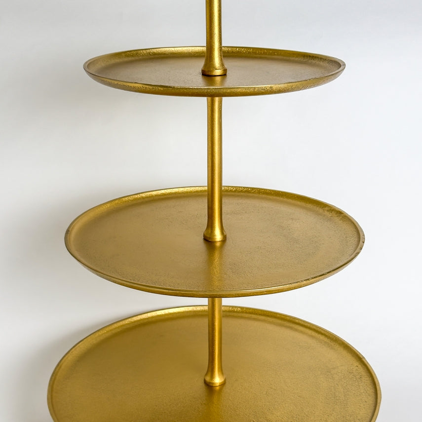Close-up of a gold 5-tier metal serving stand with round trays and a central support rod.