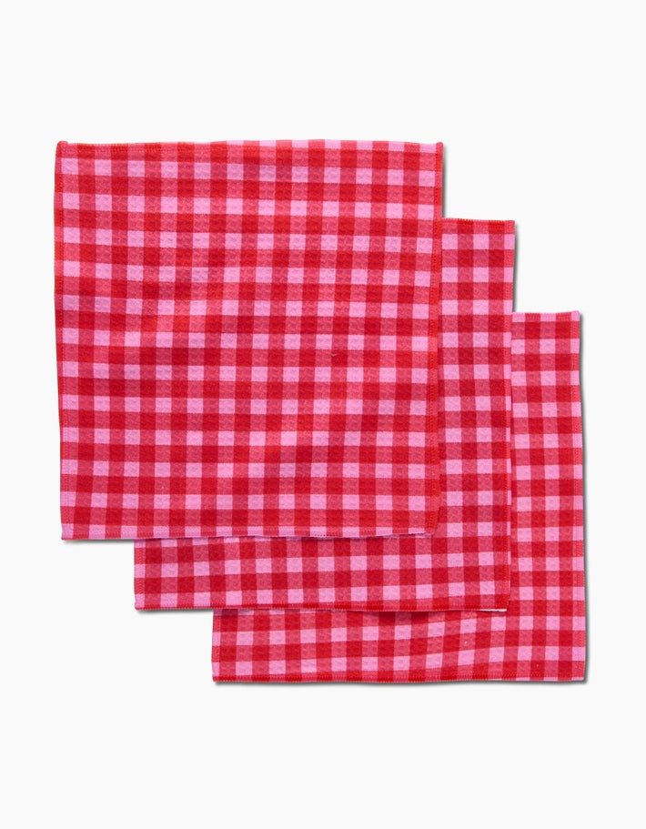 Set of three red and pink gingham waffle weave washcloths stacked diagonally.
