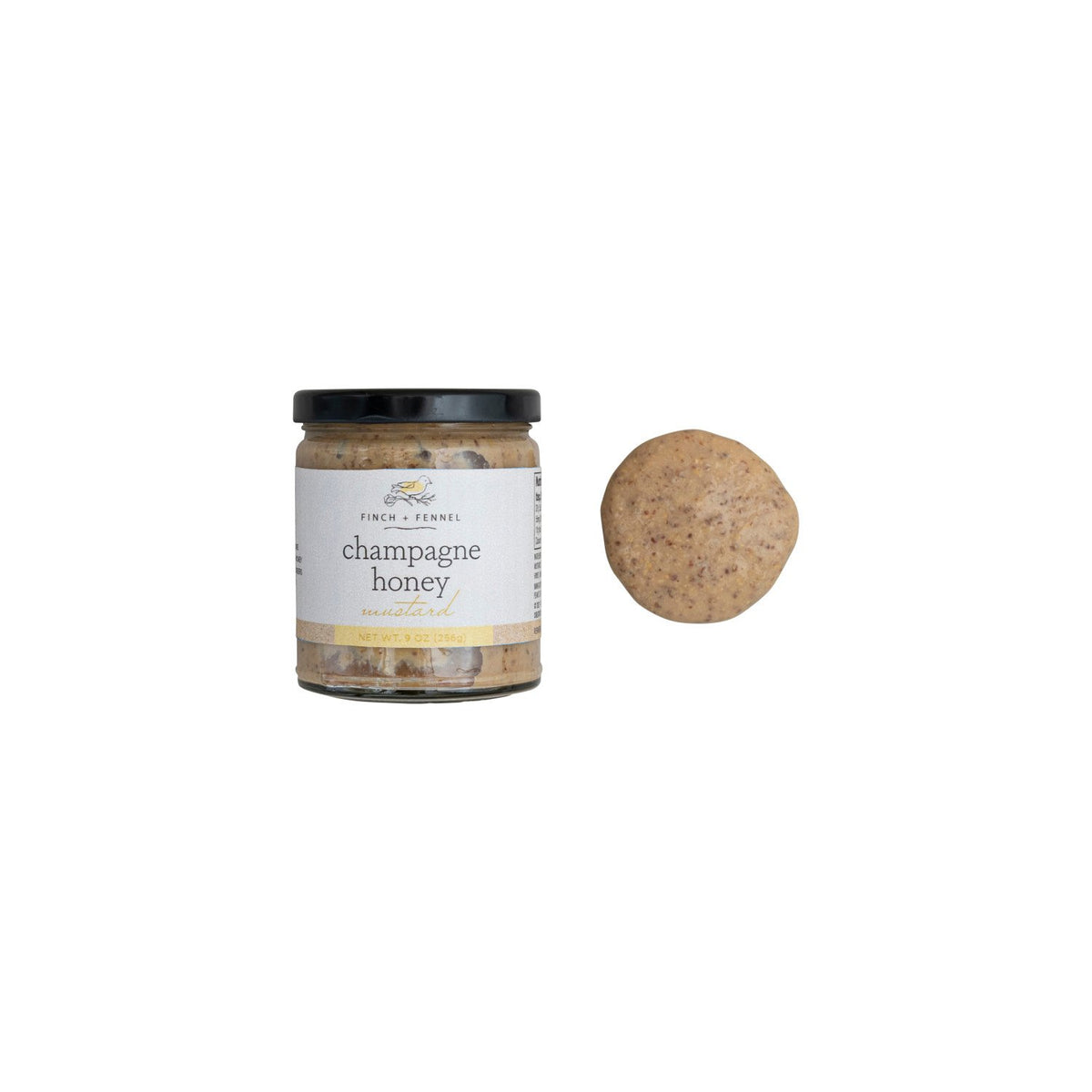 A jar of Finch + Fennel Champagne Honey Mustard next to a dollop of the mustard.