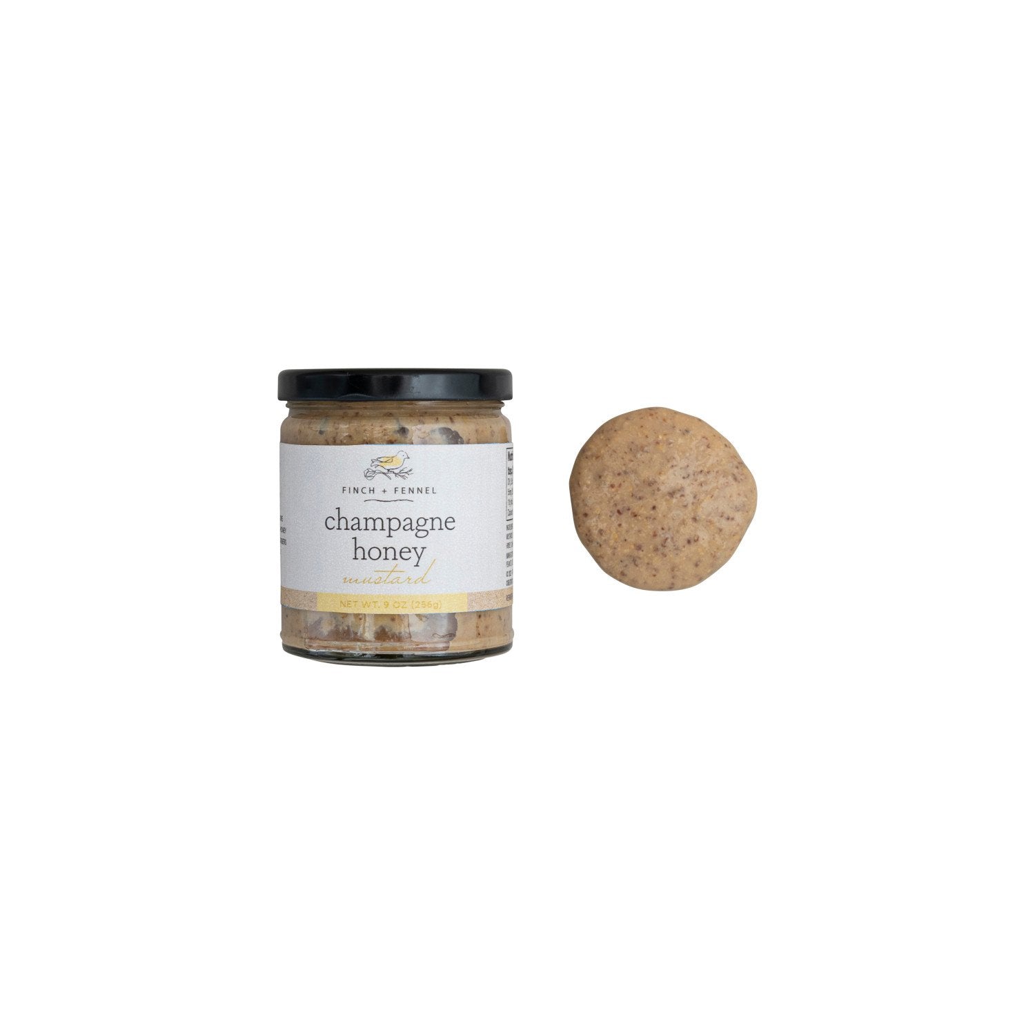 A jar of Finch + Fennel Champagne Honey Mustard next to a dollop of the mustard.