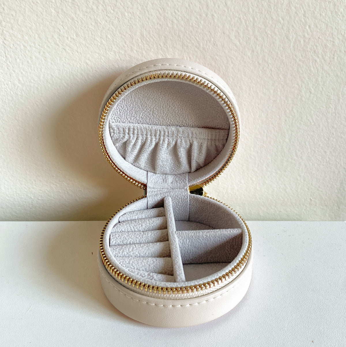 Round sorority travel jewelry case with chapter emblem featuring compartments for rings, earrings, and necklaces.
