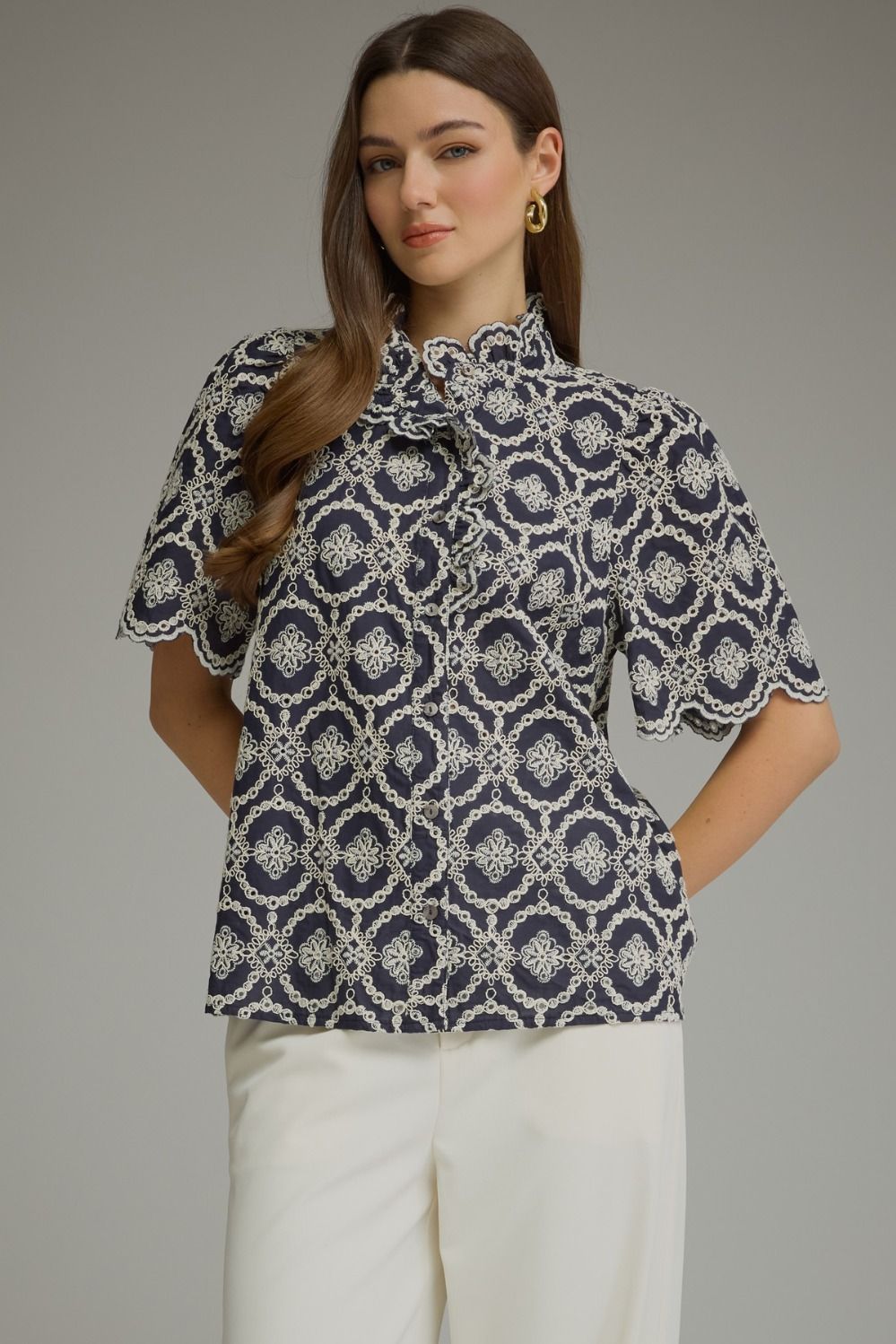 Woman wearing the Amalia navy geometric embroidered short puff sleeve top with ruffled neckline.