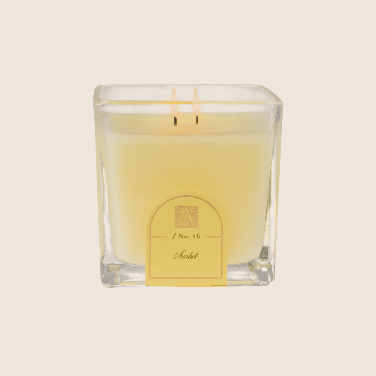 Sorbet No. 16 cube glass candle with light yellow wax and two lit wicks.