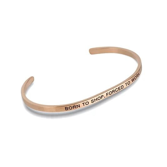 Rose gold cuff bracelet engraved with the text BORN TO SHOP, FORCED TO WORK.