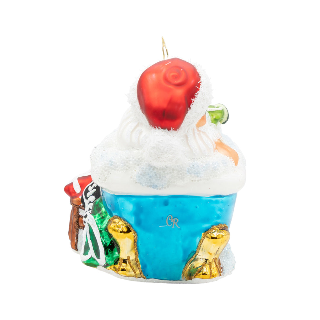 Back view of a Santa Claus glass ornament relaxing in a blue bubble bath with gold claw feet.