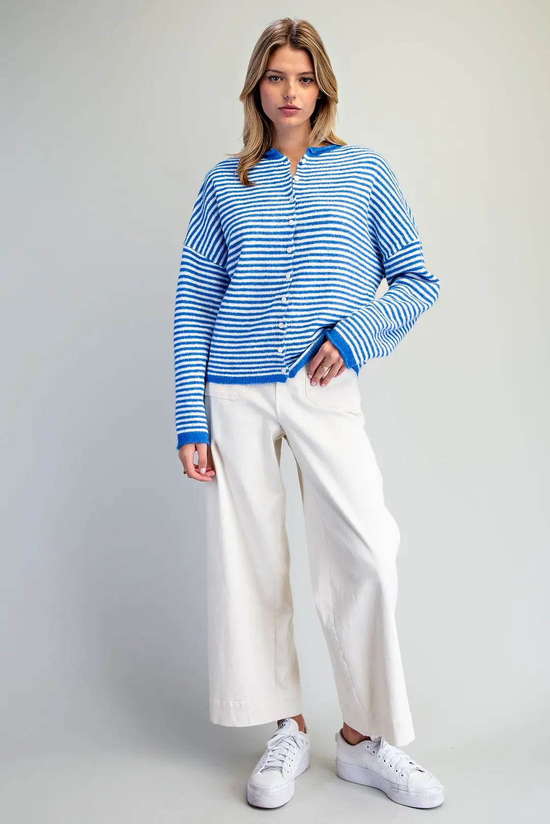 Woman wearing a blue and white Nevin Striped Knit Collared Cardigan with white wide-leg pants.