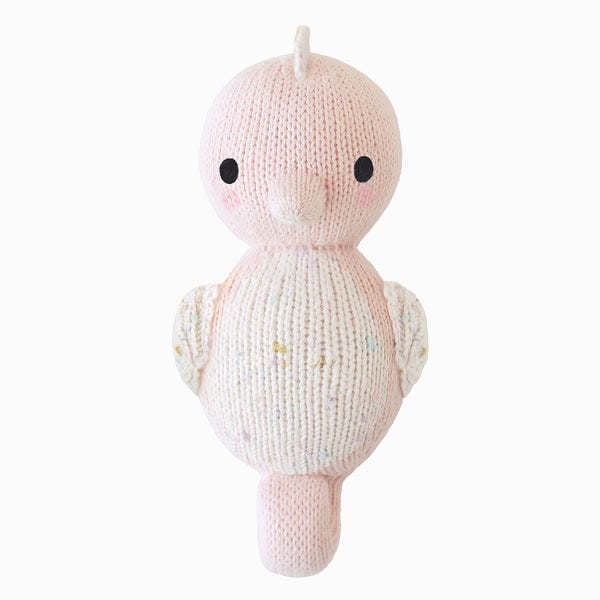 Hand-knit baby seahorse toy in powder pink cotton yarn with a soft stuffed body and small tail fin.