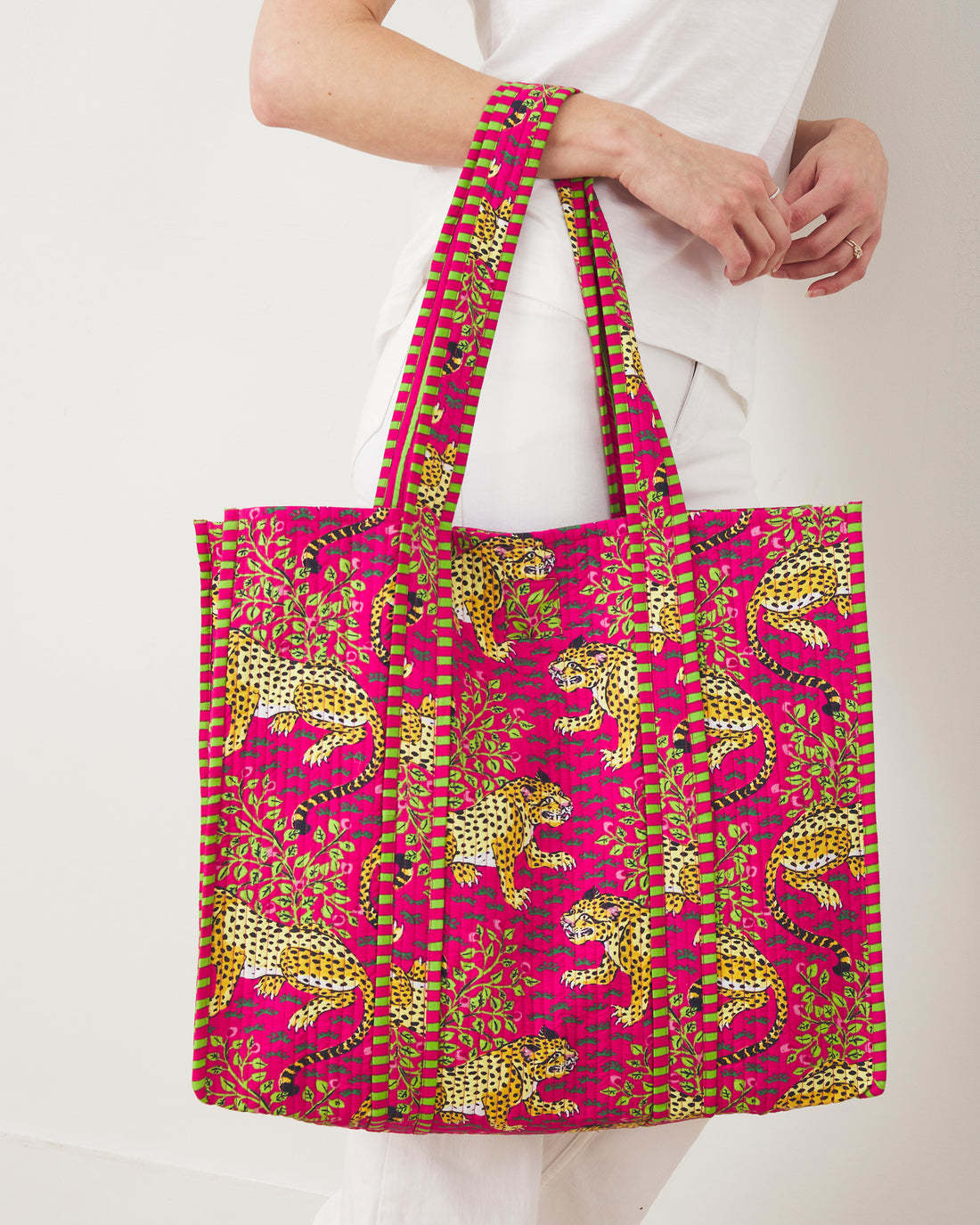 The Traveler Tote in Bagheera, a pink quilted cotton bag with a yellow leopard and vine print.
