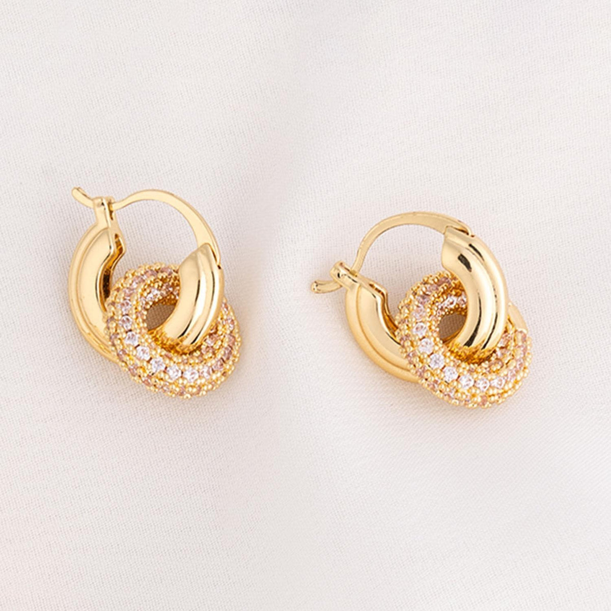 Brass plated huggie earrings with a clear cubic zirconia stone accent.