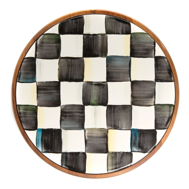 Large round trivet with an acacia wood frame and a hand-painted black and white checkered plate.