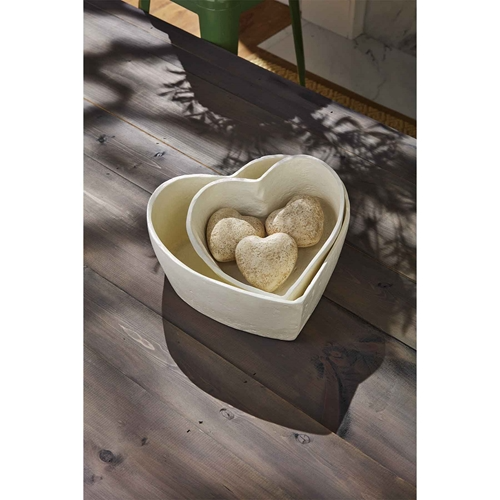 Two nested heart-shaped bowls, one inside the other, with three heart-shaped decorative stones inside the smaller bowl.