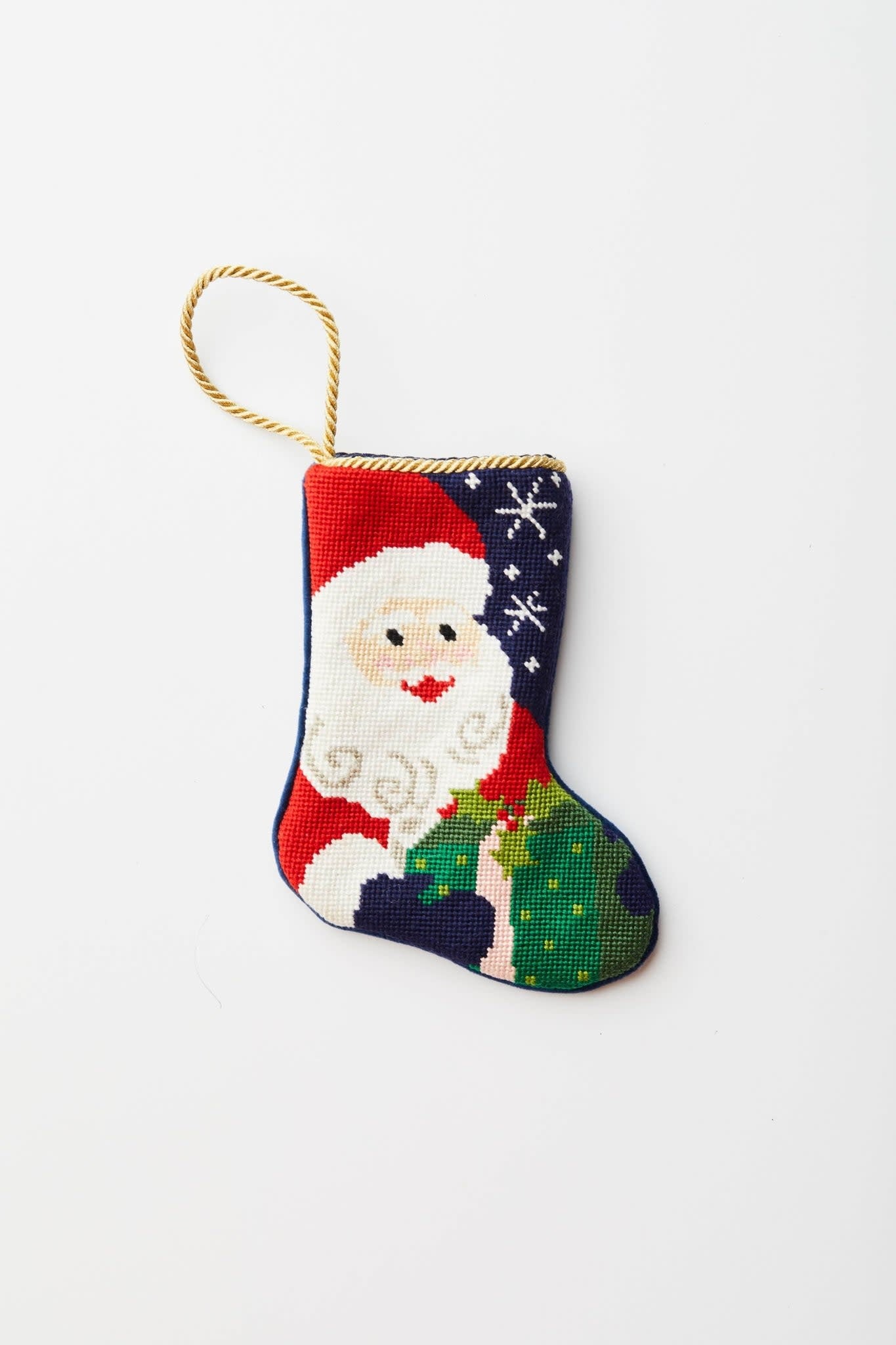 Hand-stitched needlepoint Santa stocking with velvet backing in red featuring white snowflake pattern