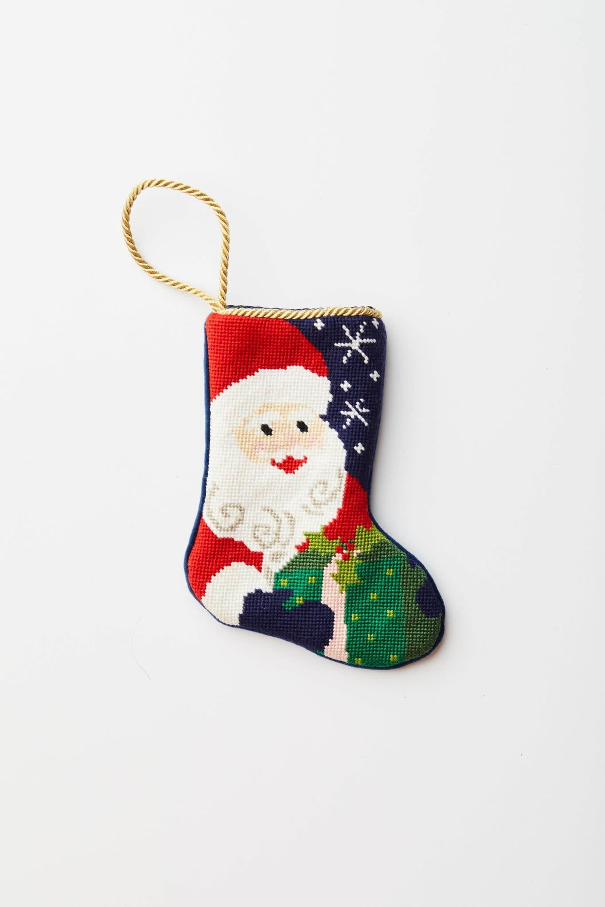 Hand-stitched needlepoint Santa stocking with velvet backing in red featuring white snowflake pattern