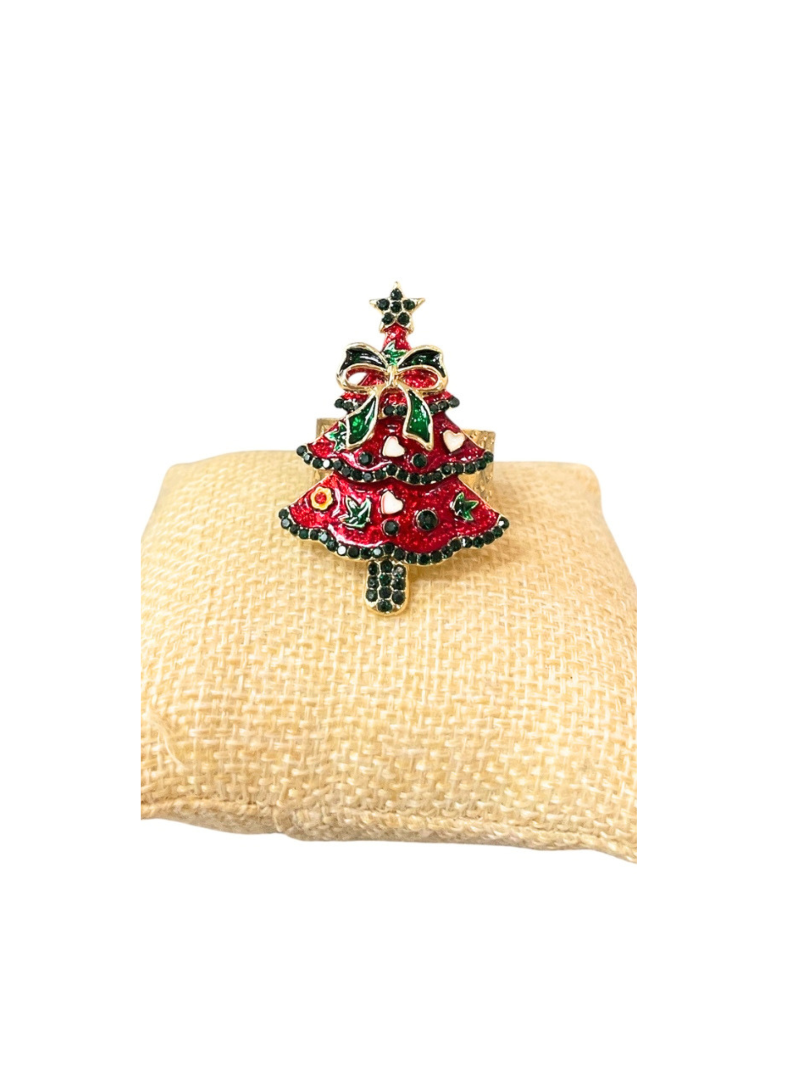 Gold Christmas tree ring with red enamel, green bow, and colorful crystal accents on a tan cushion.