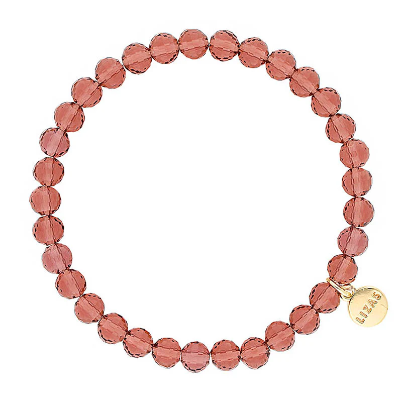 Lizas Quadro Big crystal stretch bracelet in dusty rose with a gold logo charm.
