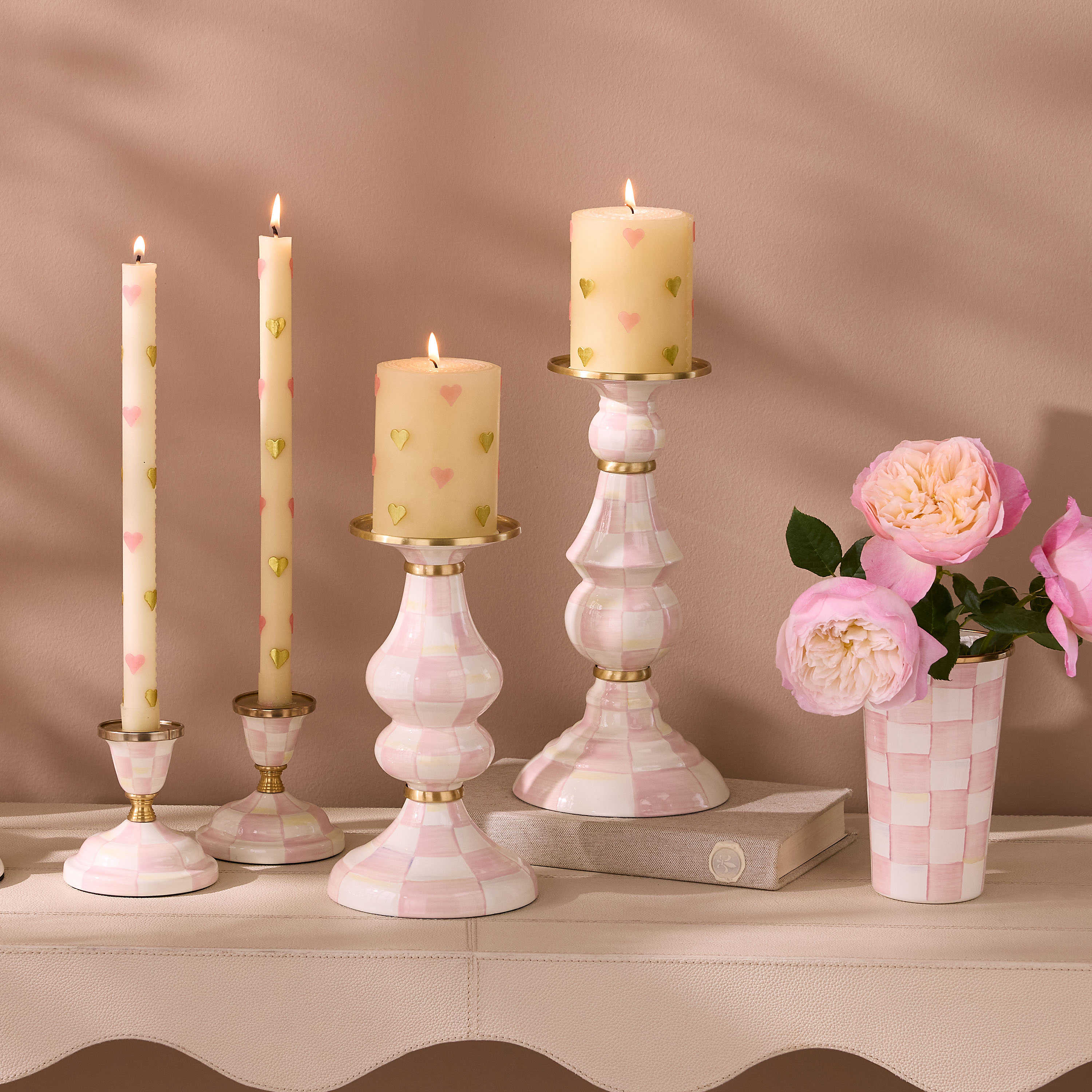 Hand-painted pink and white checkered pillar candlestick with brass accents and a lit candle.