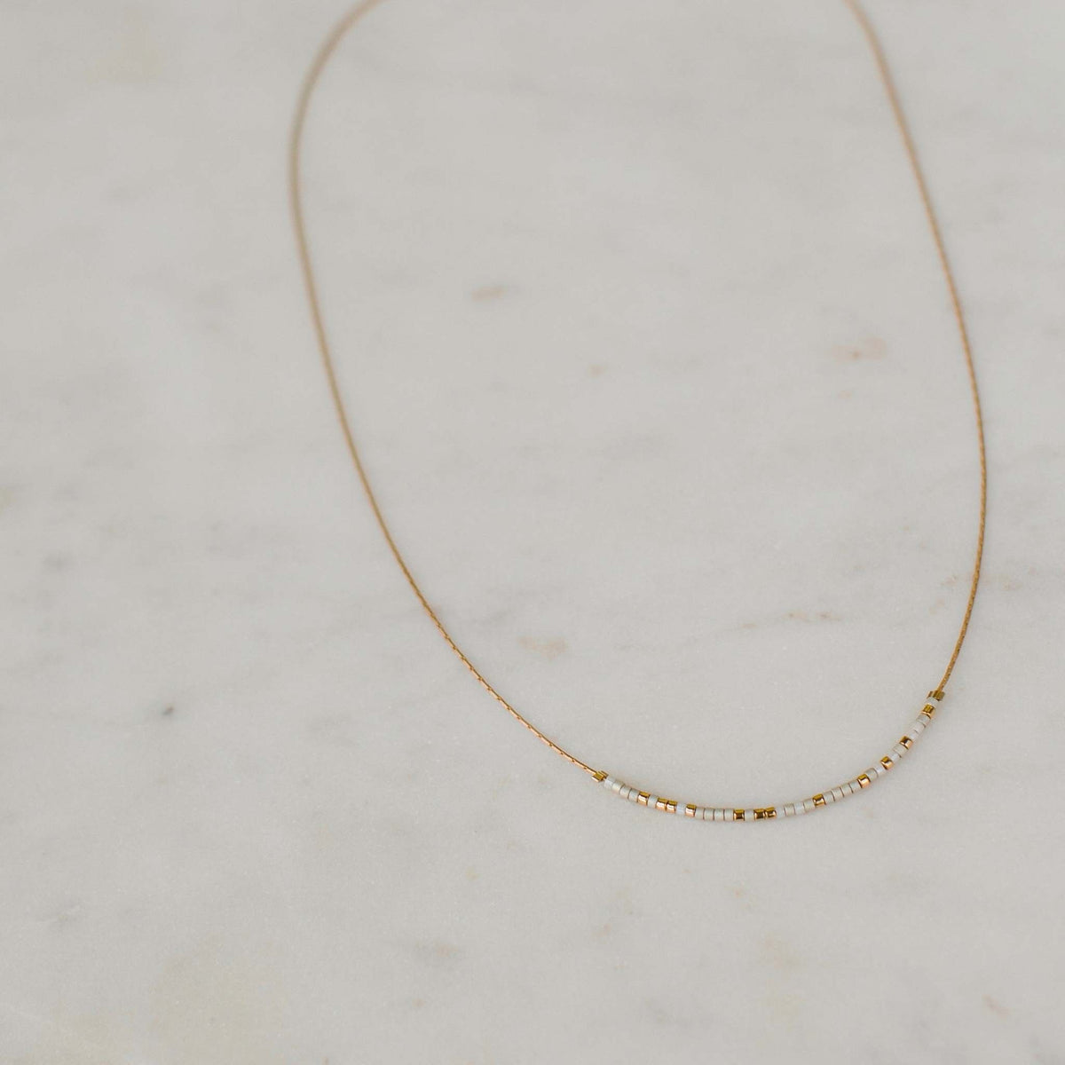 Pearl and alabaster Be the Change necklace with Morse code message on a standard length chain.