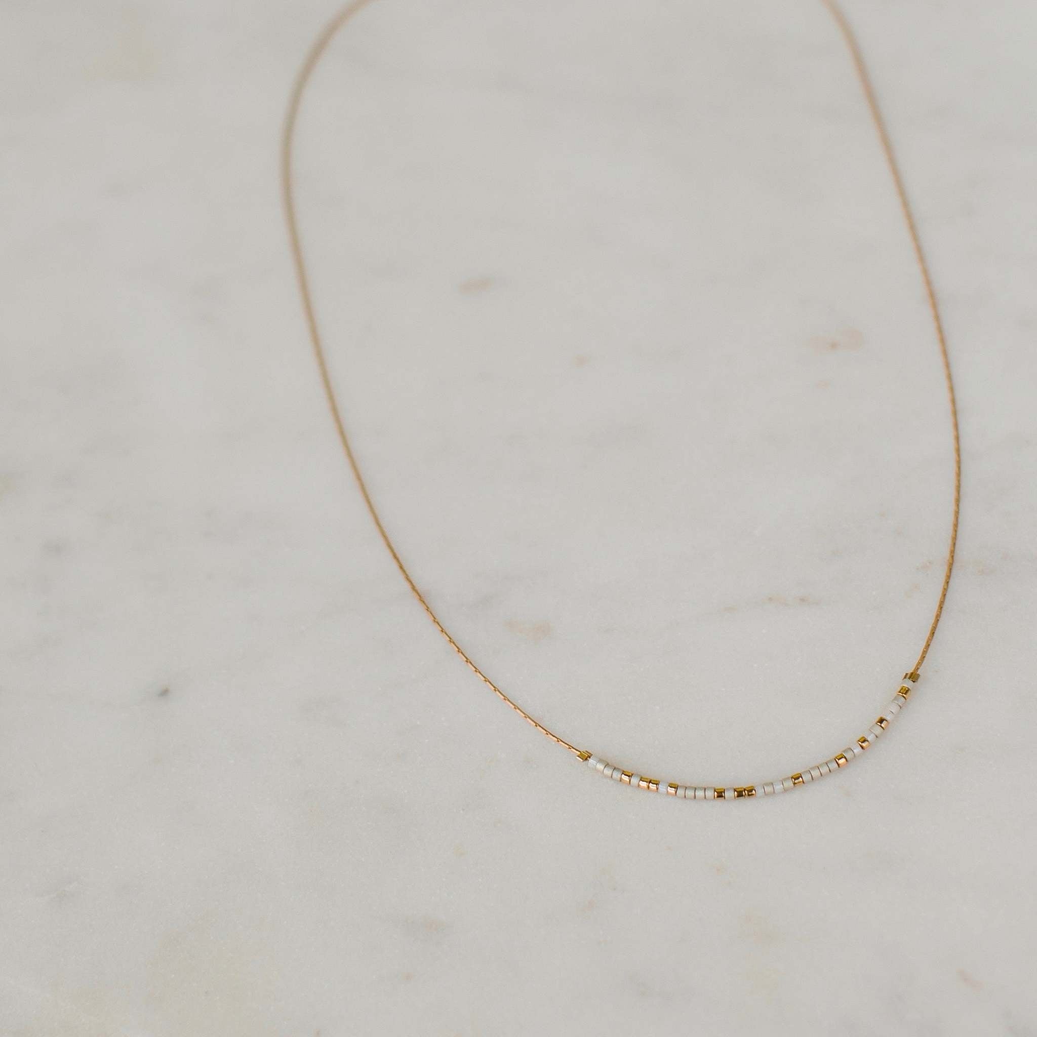Pearl and alabaster Be the Change necklace with Morse code message on a standard length chain.