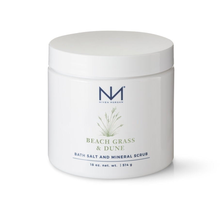 Glass jar containing beige bath salts with a white lid labeled Beach Grass & Dune Bath Salts.