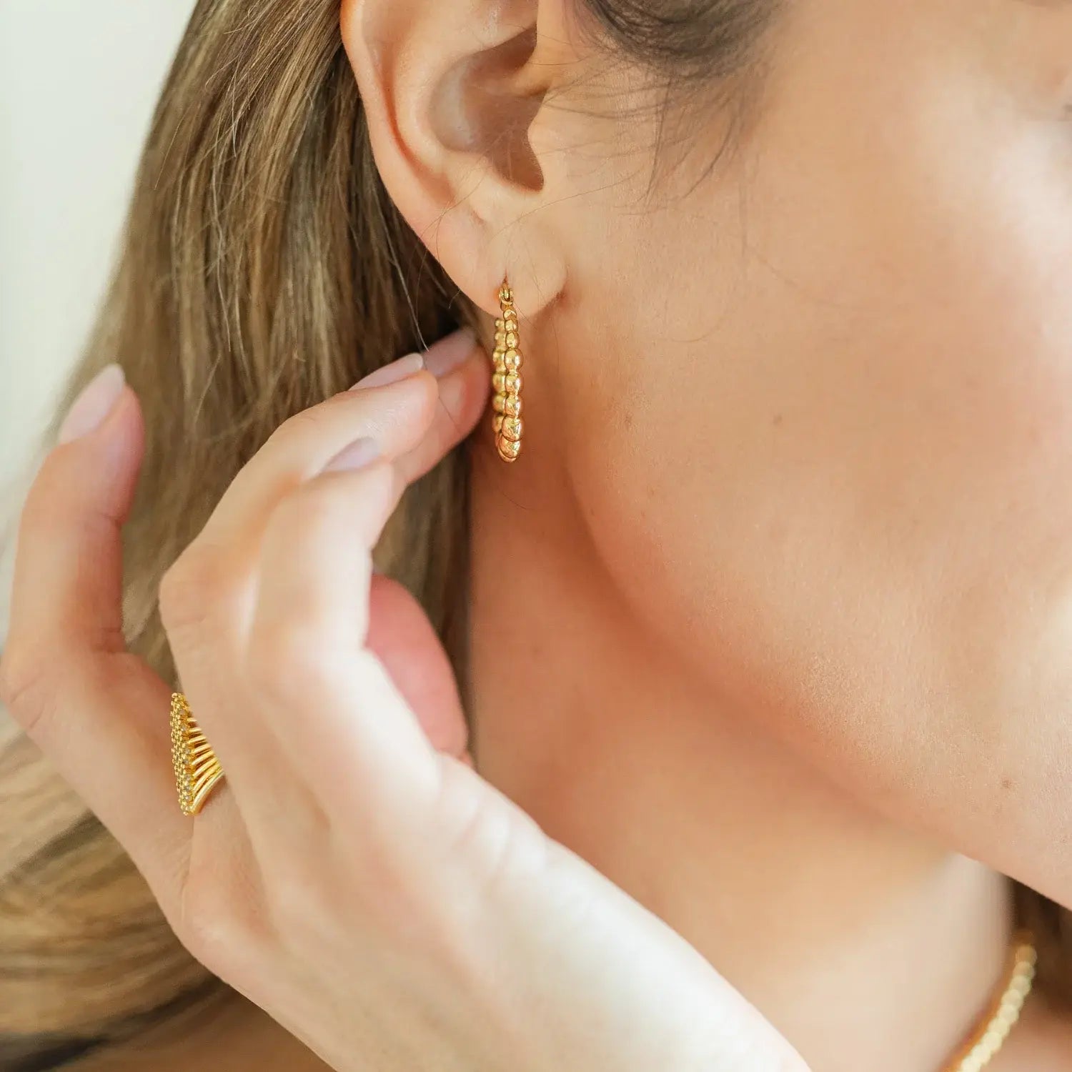 Gold plated brass latchback hoop earrings with a delicate beaded pattern.