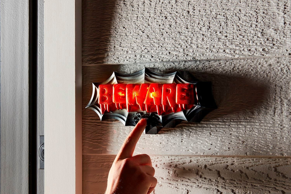Plastic Halloween door decor shaped like a skull with glowing eyes on a black background.