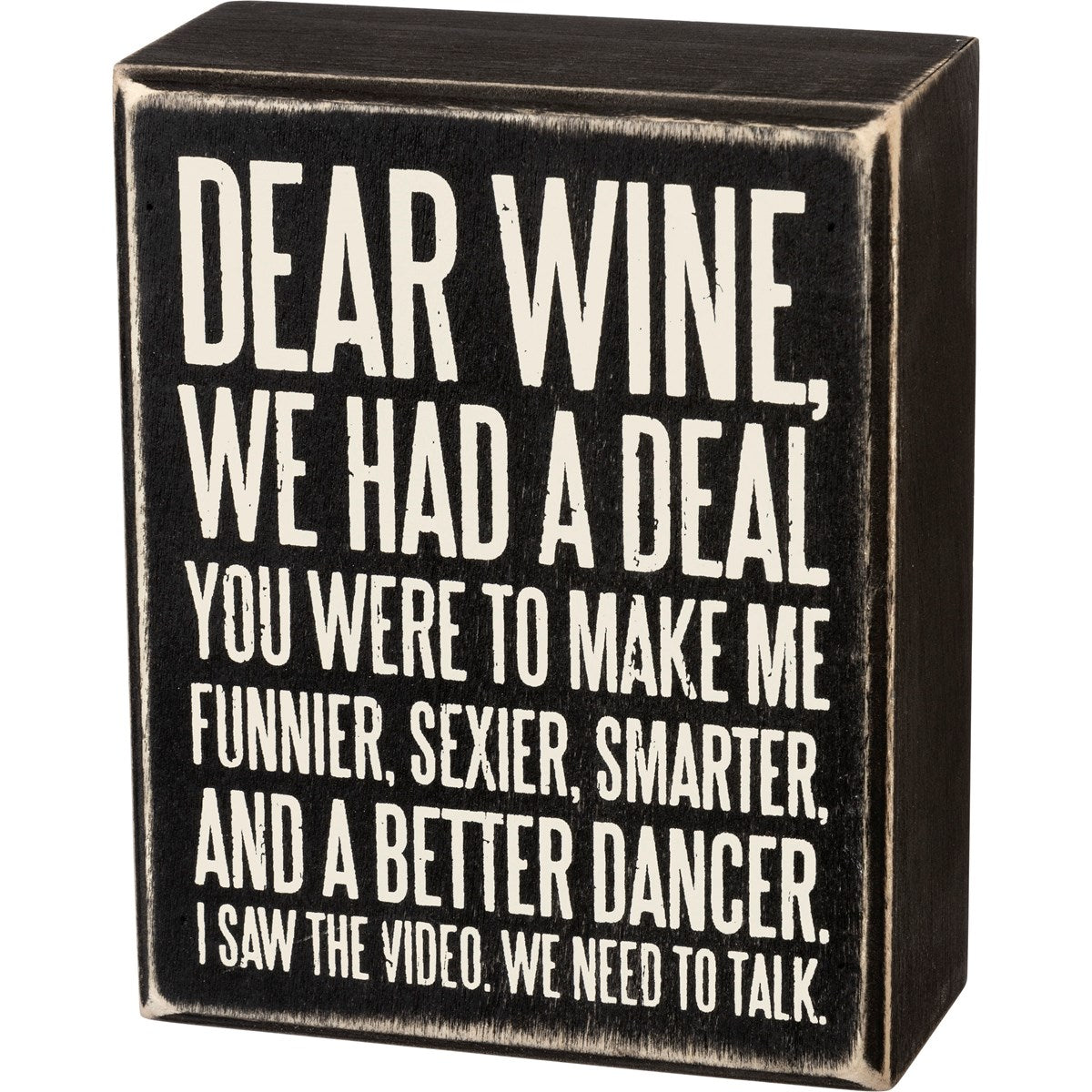Black wooden box sign with white text that reads 'Dear Wine, We Had A Deal. You Were To Make Me Funnier, Sexier, Smarter, And A Better Dancer. I Saw The Video. We Need To Talk.'