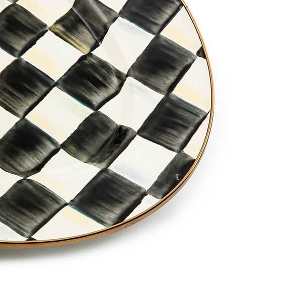 Close-up of a small oval platter with hand-painted black and white checks and a bronzed steel rim.