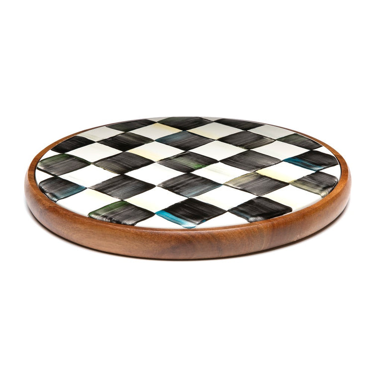 Large round trivet with a black and white hand-painted checkered pattern and an acacia wood base.