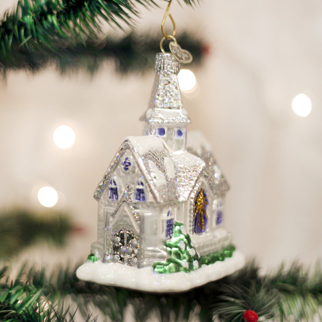 Sparkling glass cathedral ornament with white glitter snow, blue windows, and a green tree.