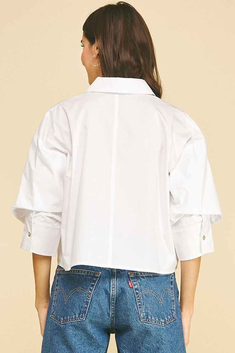 Back view of a white cropped button-down shirt with tuck detailed 3/4 sleeves and a classic collar.
