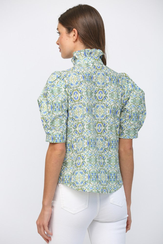 Back view of a woman wearing a green and blue patterned ruffle neck top with puff short sleeves.