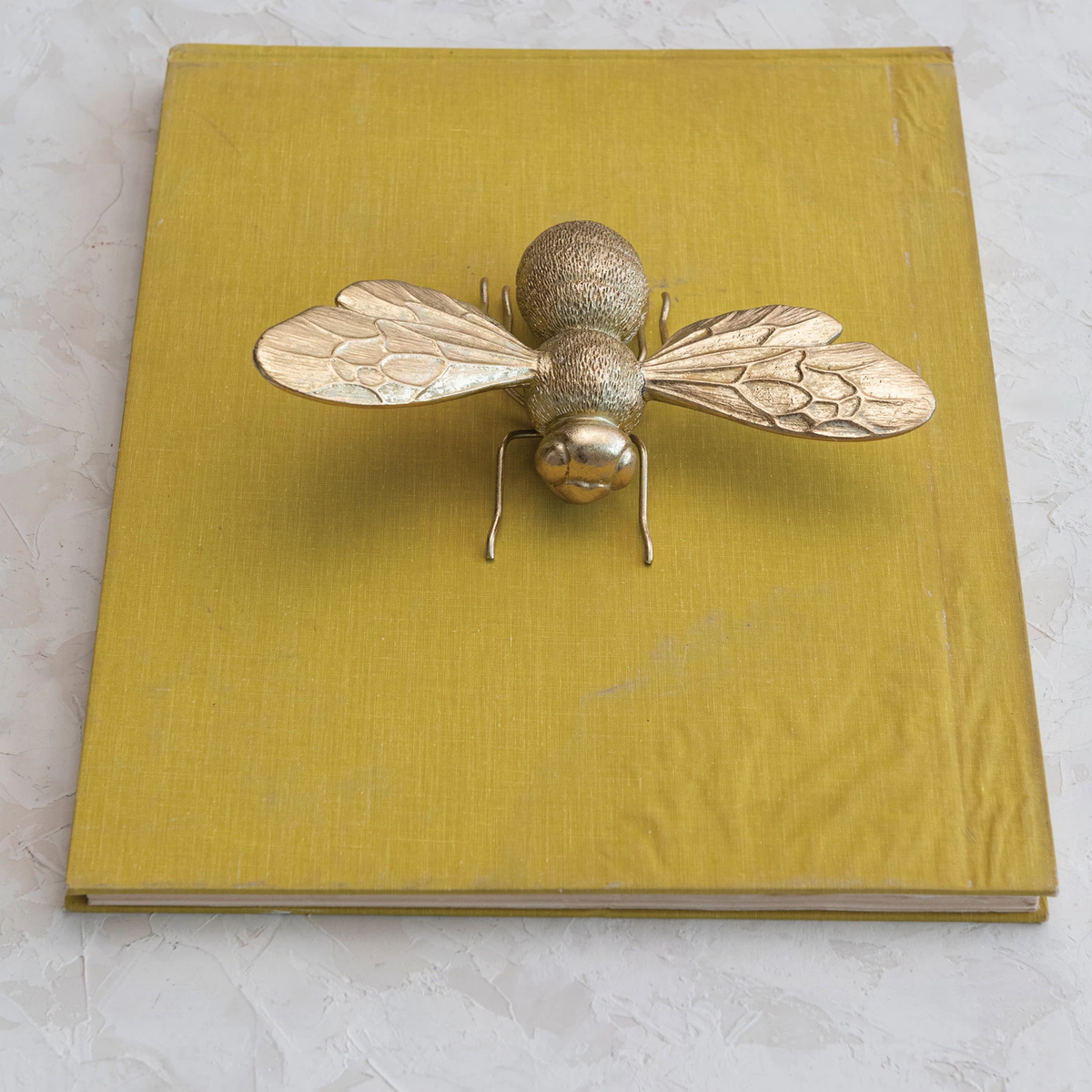 Gold-finish resin bee figurine with pewter accents on a black background