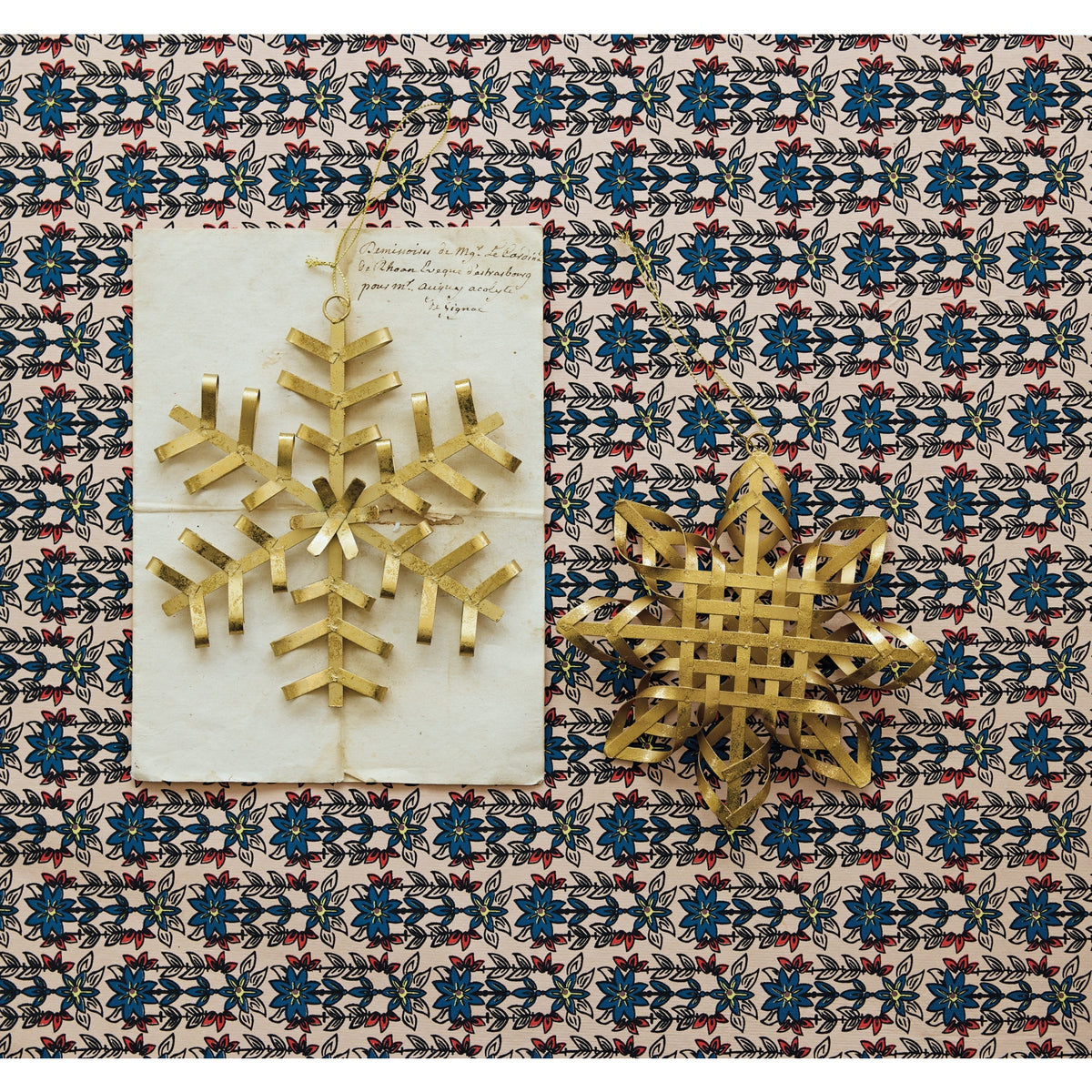 Two gold iron snowflake ornaments with a distressed finish on a patterned background.